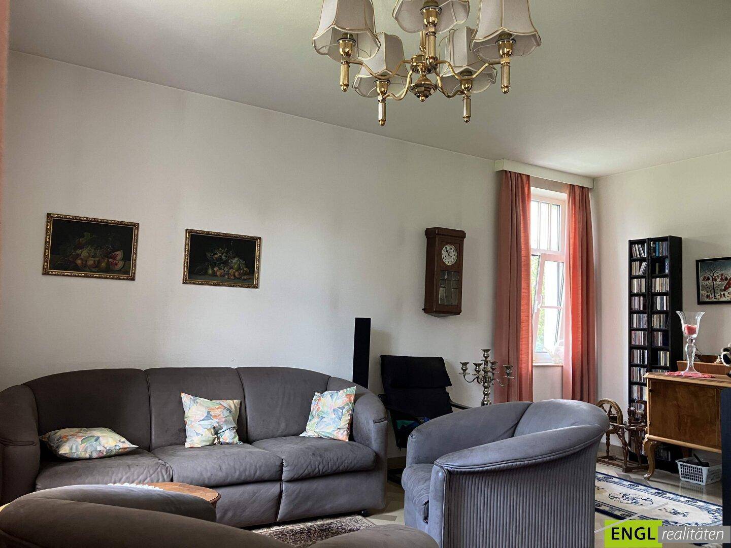 Klassisches Wohnzimmer mit bequemen Sofas, traditionellem Kronleuchter und Fenstern.