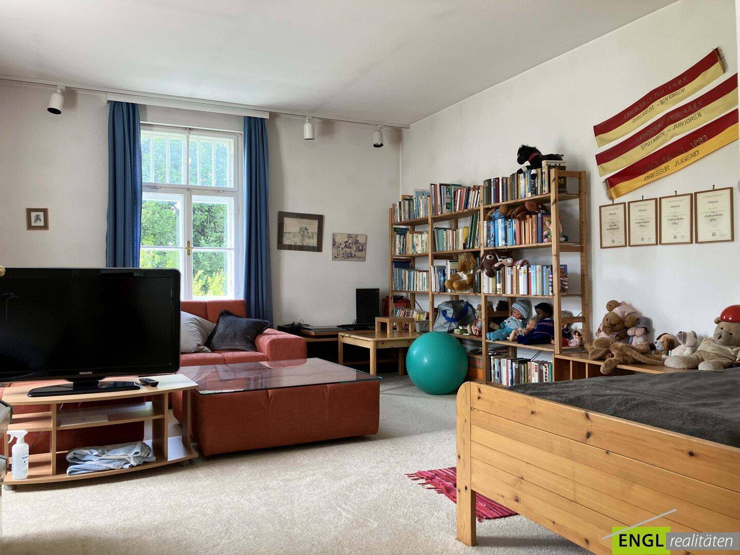 Geräumiges Schlafzimmer mit einem Bett, großem Bücherregal und viel natürlichem Licht.