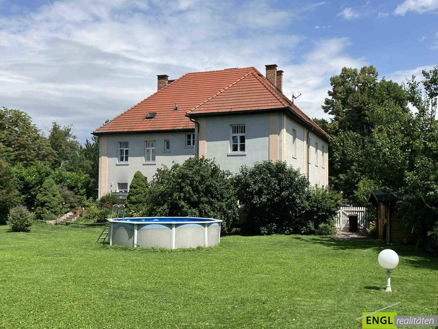 Rückansicht des Hauses mit weitläufigem Garten, Aufstellpool und einem kleinen Gartenhaus.