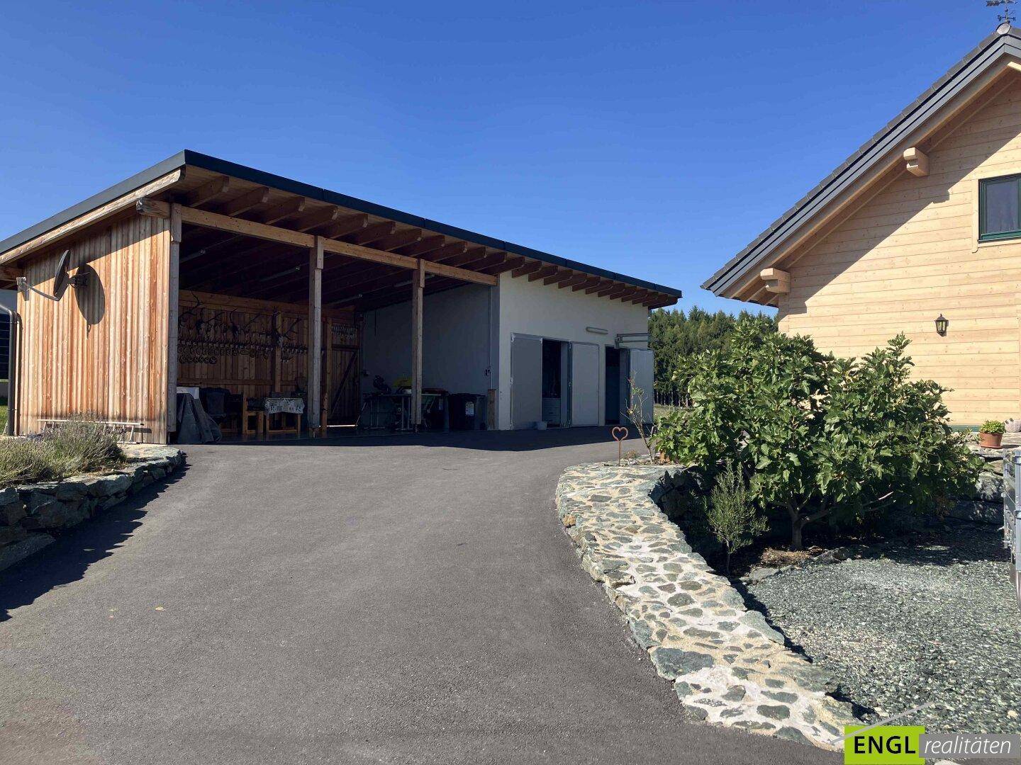 Zufahrt zum Anwesen mit Carport und Nebengebäude in ländlicher Umgebung.