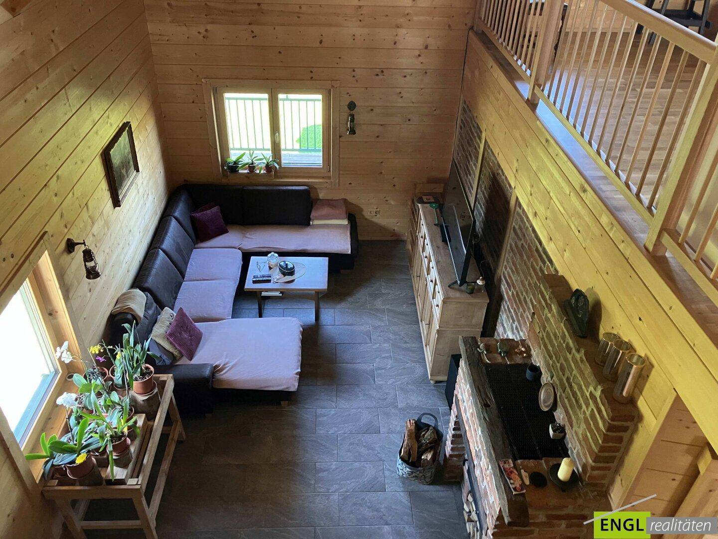 Gemütliches Wohnzimmer mit Holzwänden, Kamin und Galerieblick.