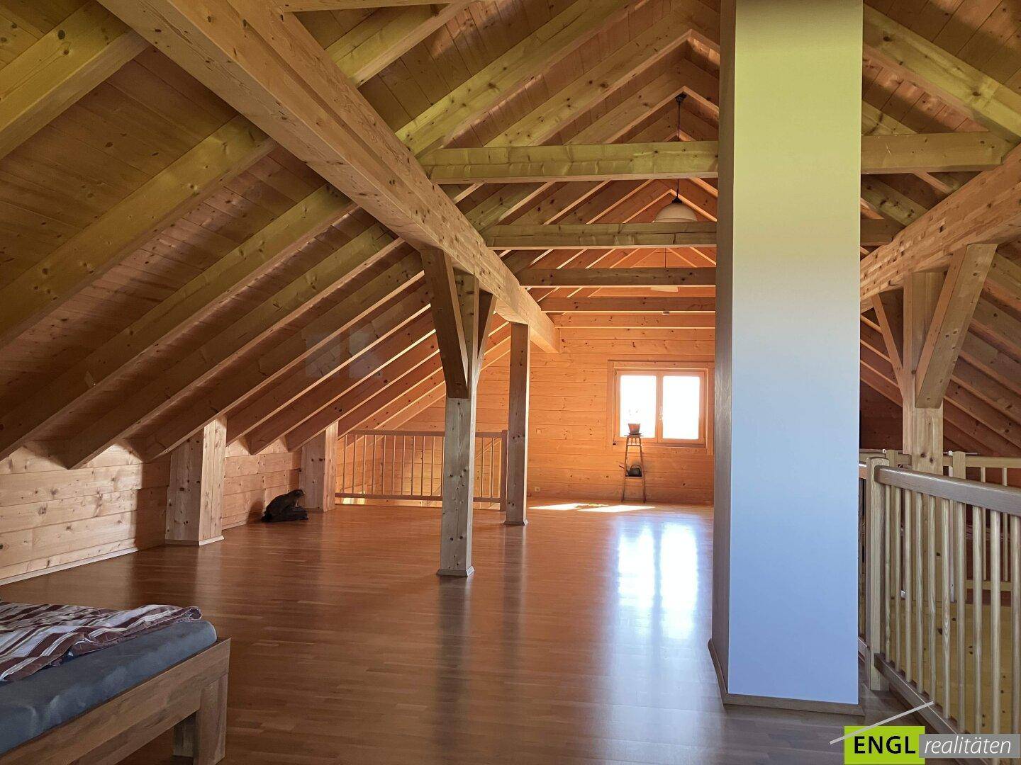 Geräumiger Dachbodenbereich mit sichtbaren Holzbalken und Holzboden.