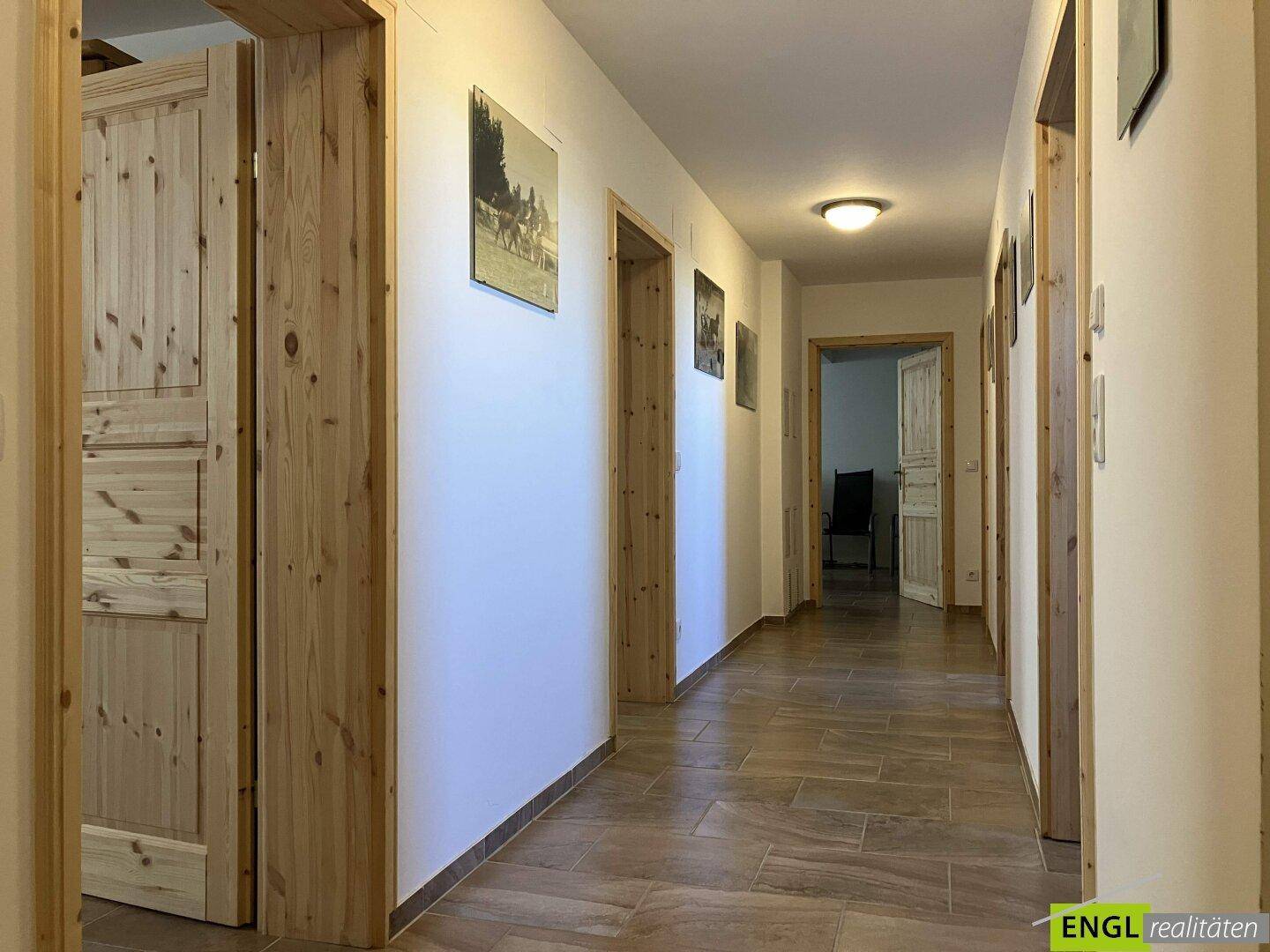 Heller Flur mit Holztüren und Fliesenboden, der zu weiteren Räumen führt.