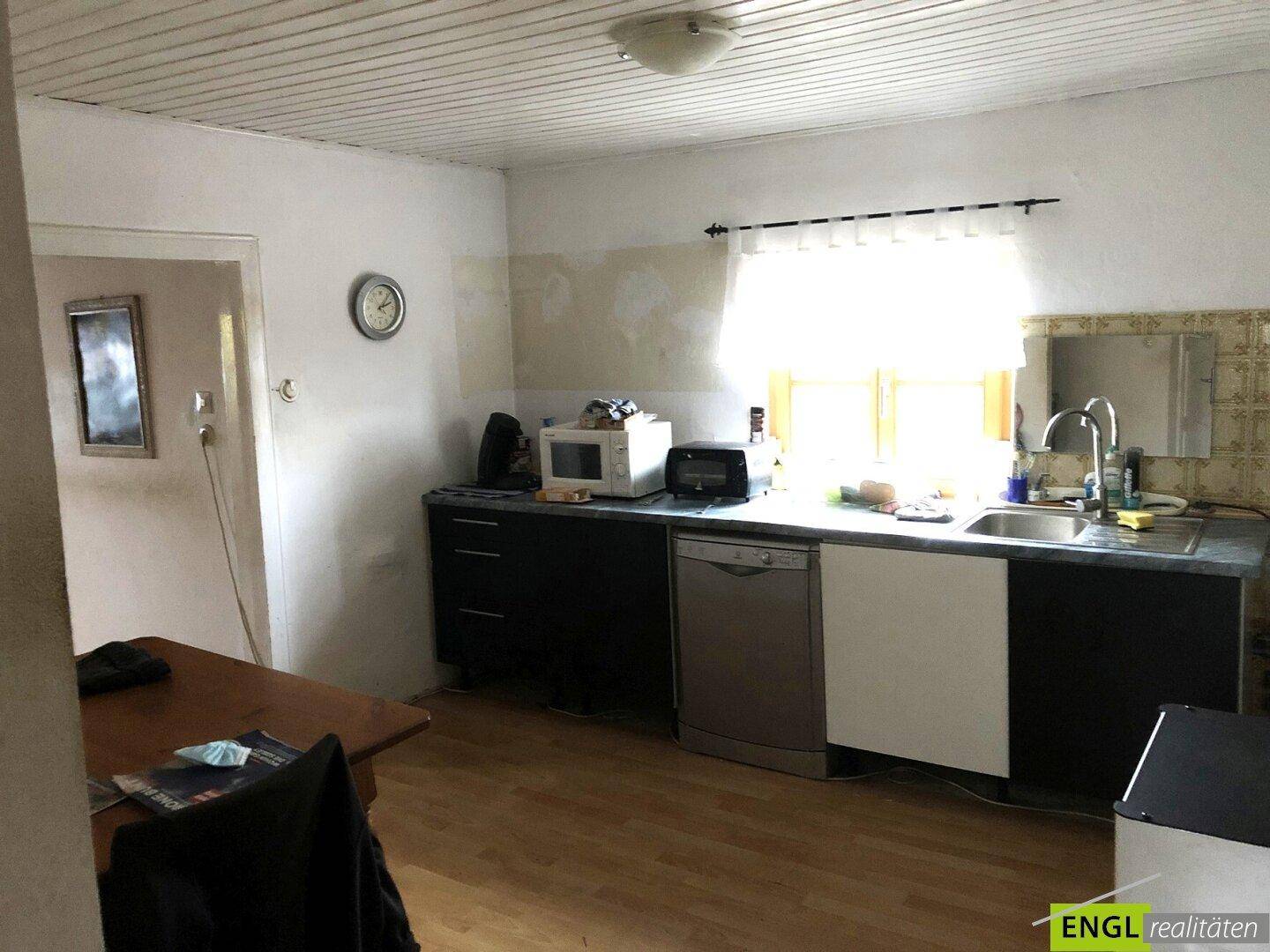 Funktionale Küche mit Holzdecke, Spülmaschine und Mikrowelle, bietet ausreichend Arbeitsfläche und Stauraum.