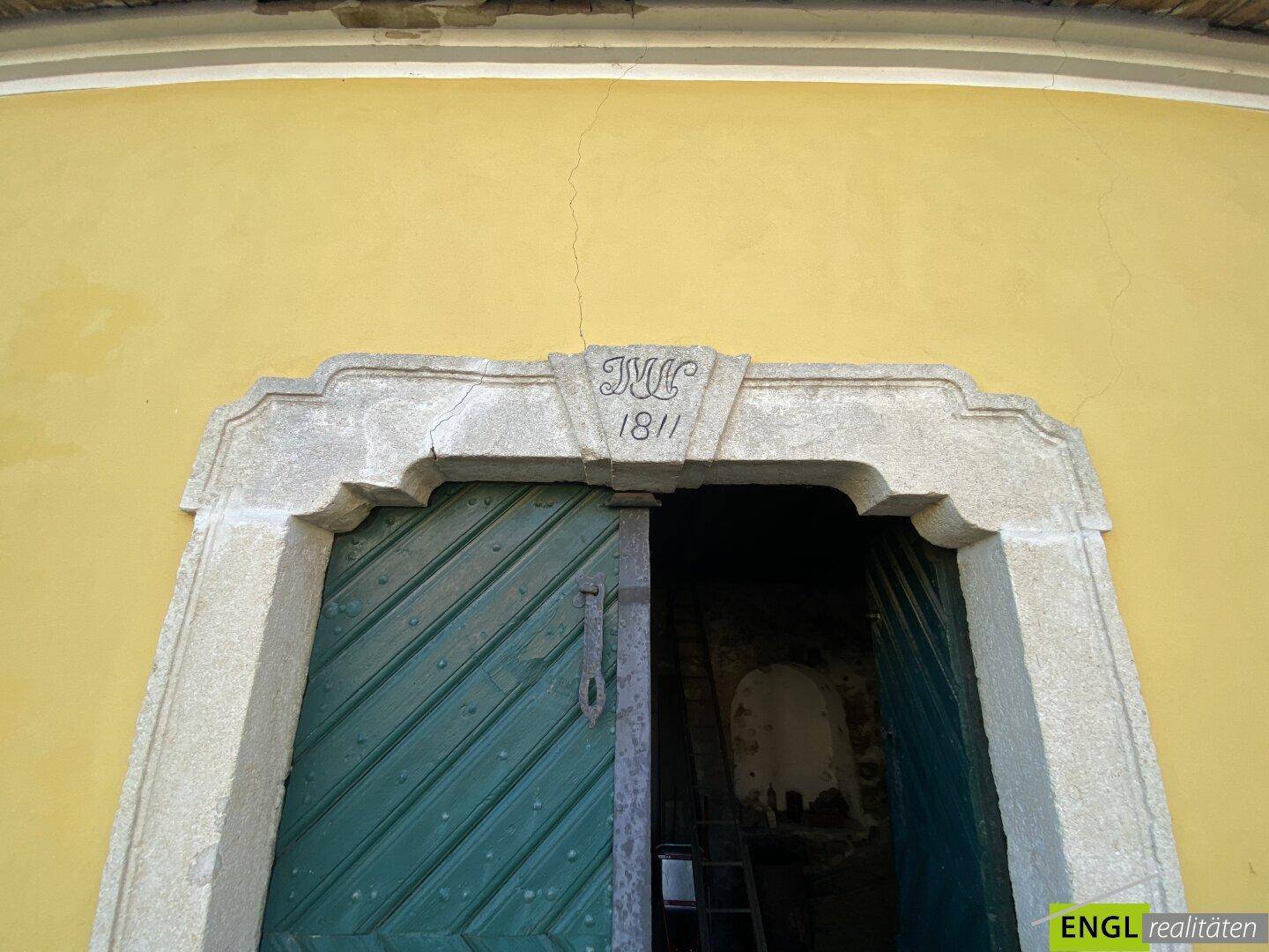 Historischer Steintürrahmen mit der Jahreszahl 1811 über einer grünen Holztür an einer gelben Fassade.