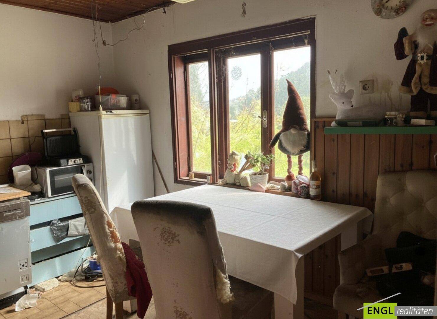Kleine Küche mit Esstisch, Kühlschrank und Blick auf die umliegende Landschaft.