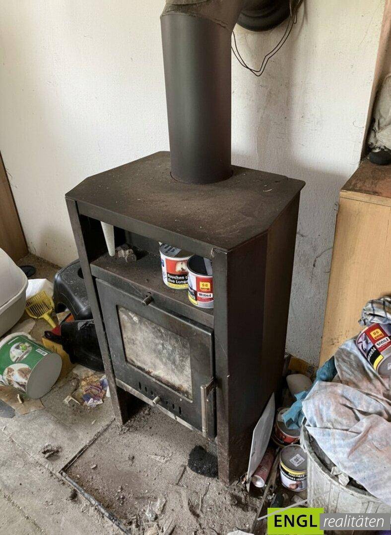 Detailansicht eines rustikalen Holzofens, der als Heizquelle dient.