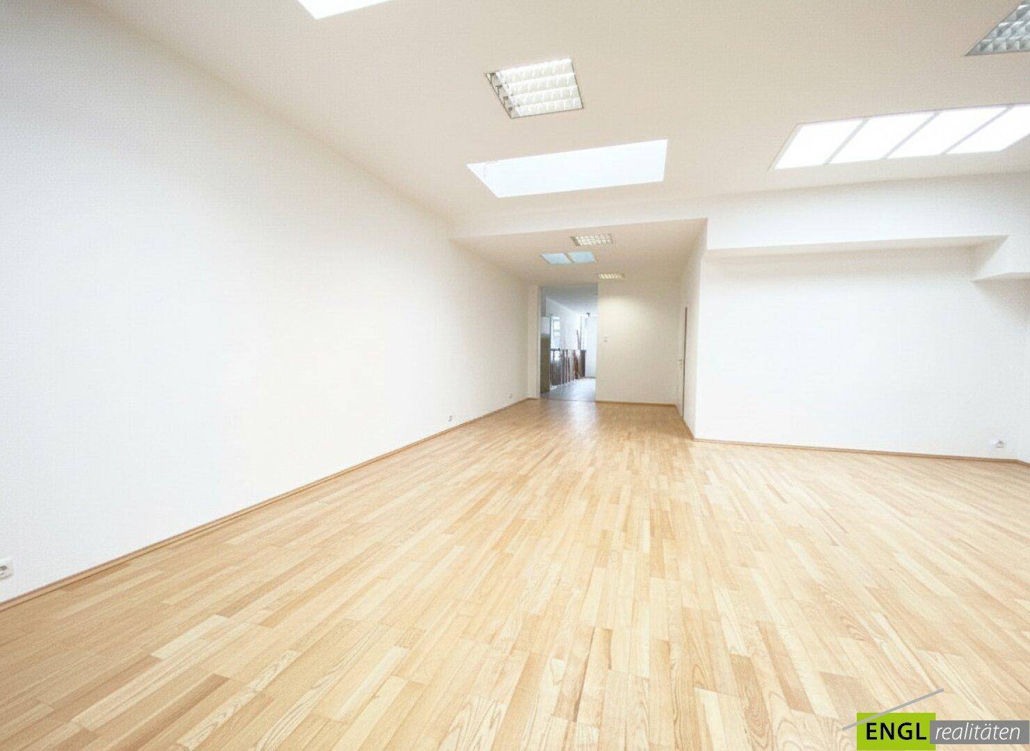 Langer, leerer Büroraum mit Holzboden und weißen Wänden, bietet viel Platz für verschiedene Nutzungen.