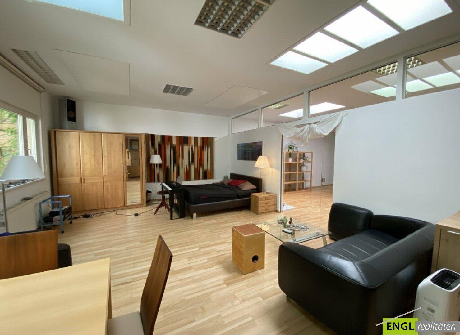 Schlafzimmer mit Doppelbett, Nachttischen und großem Holzschrank, kombiniert mit Wohnbereich.