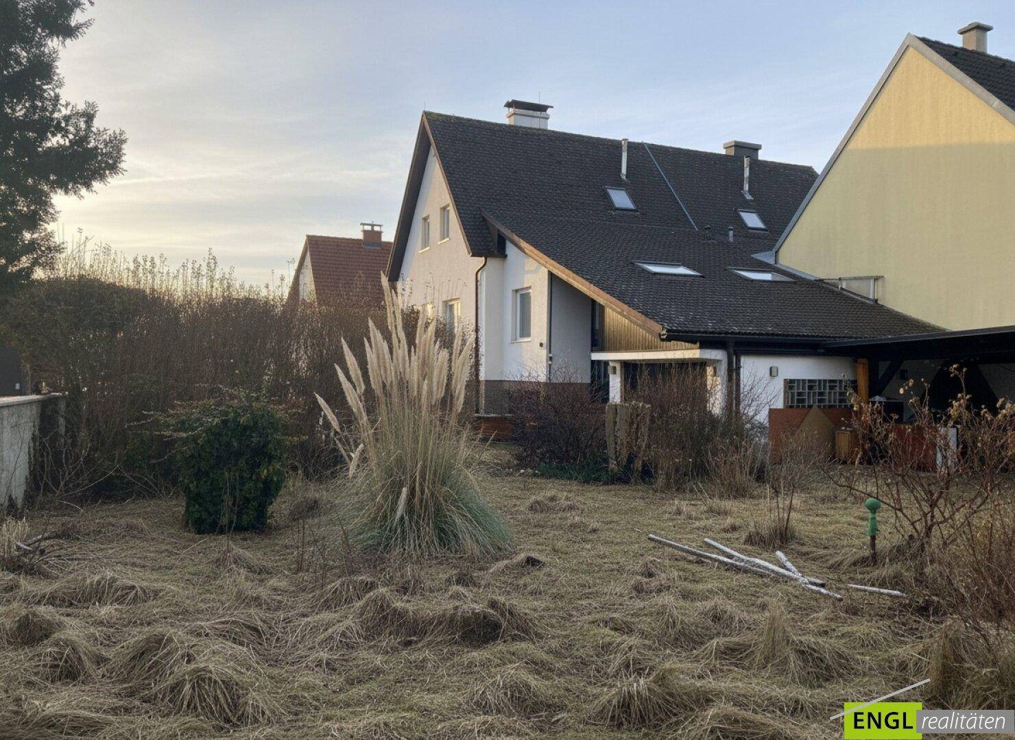 Rückansicht des Hauses mit ungepflegtem Gartenbereich und Blick auf Nachbargebäude.