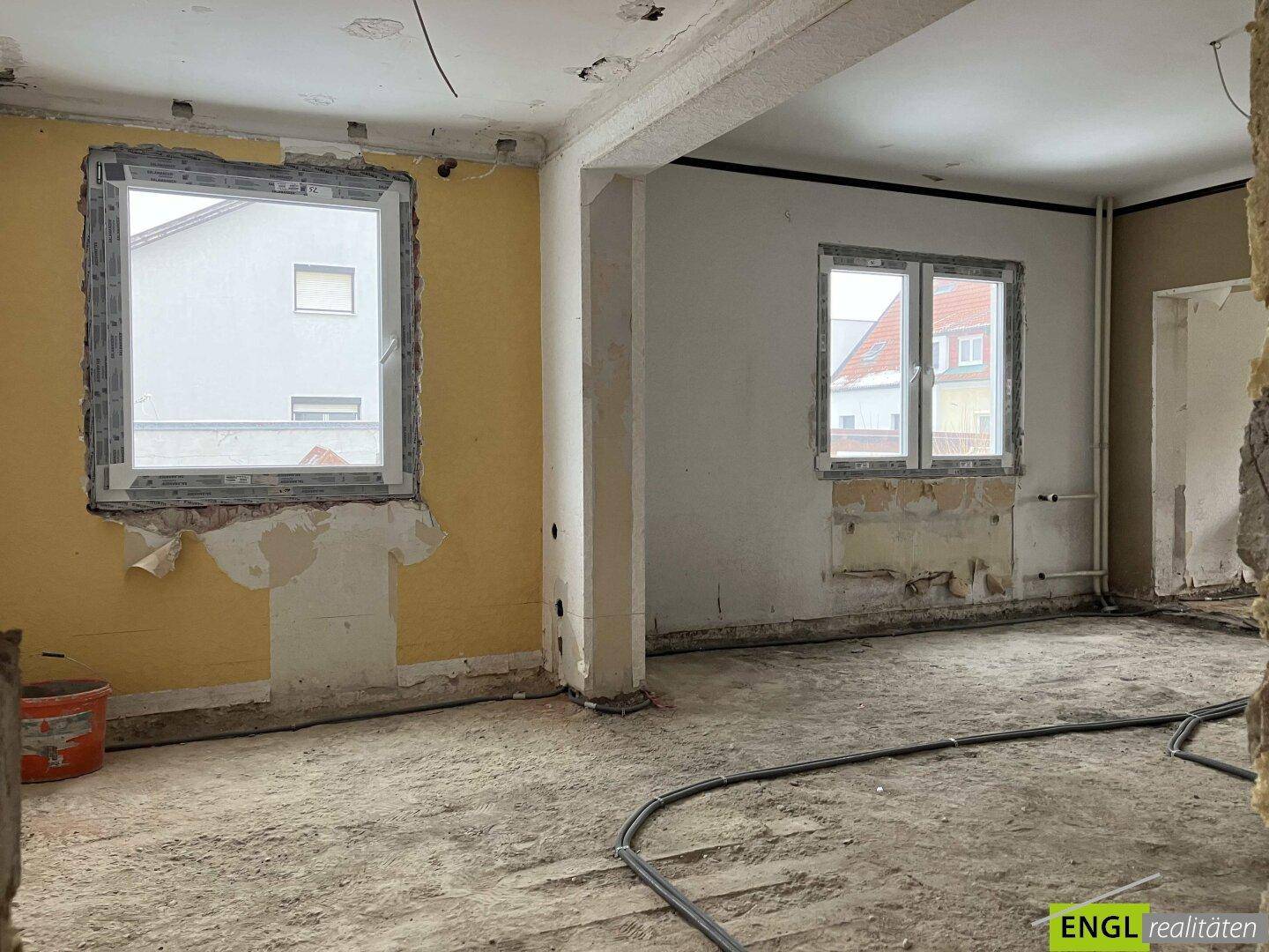 Innenraum im Rohbauzustand mit sichtbaren Fenstern und vorbereiteten Installationen.