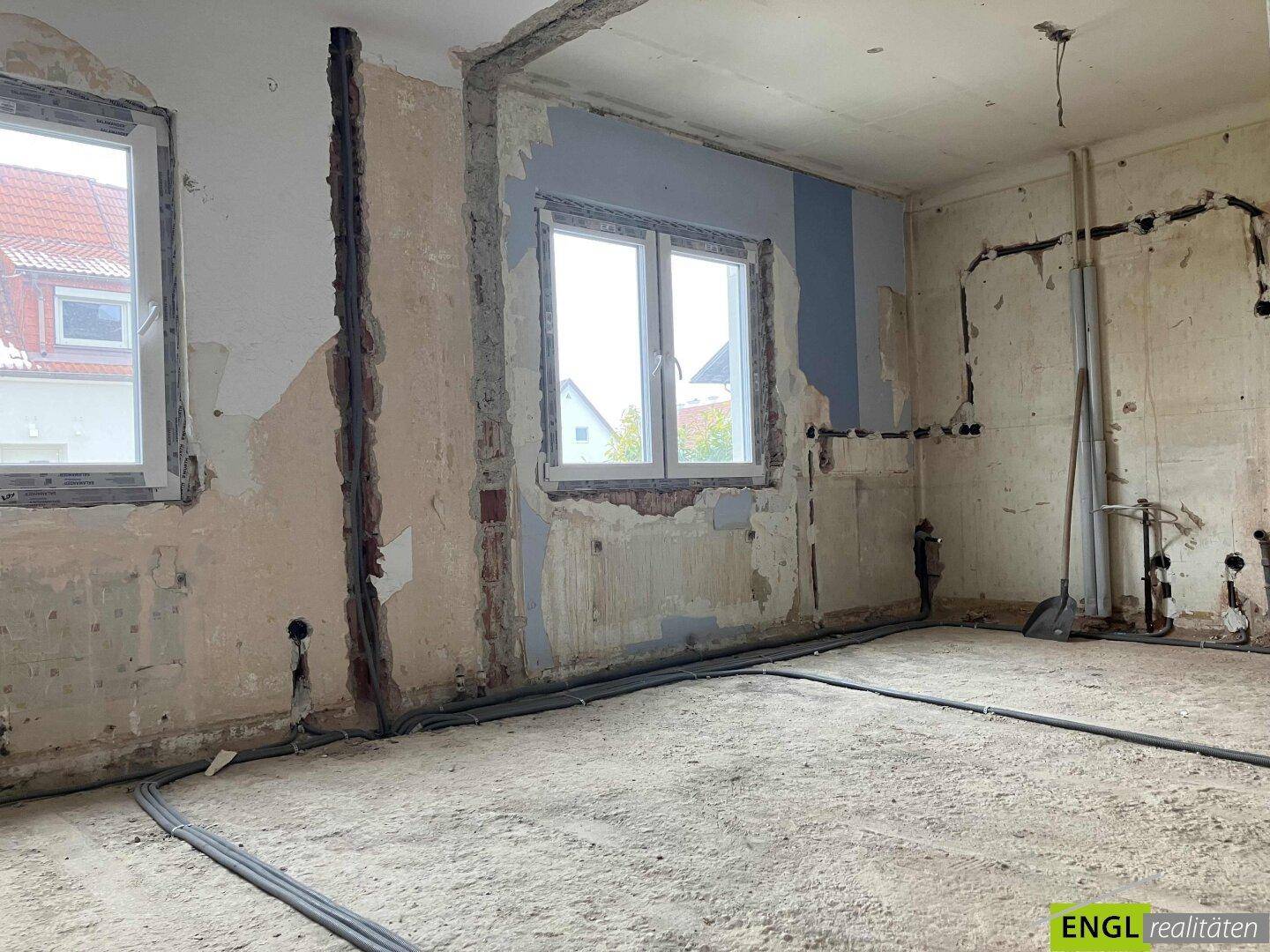 Raum im Umbau mit neuen Fenstern und sichtbaren Wandinstallationen für zukünftige Nutzung.