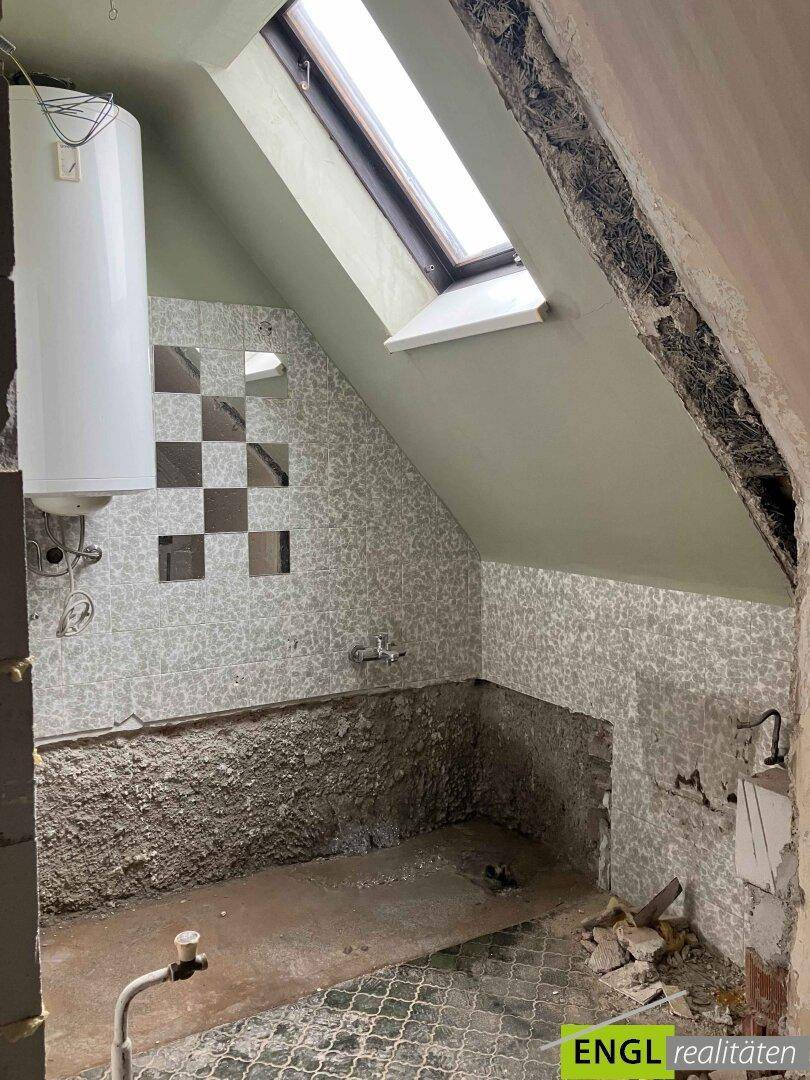 Badezimmer im Dachgeschoss im Rohbau mit Dachfenster und vorbereiteten Fliesenflächen.