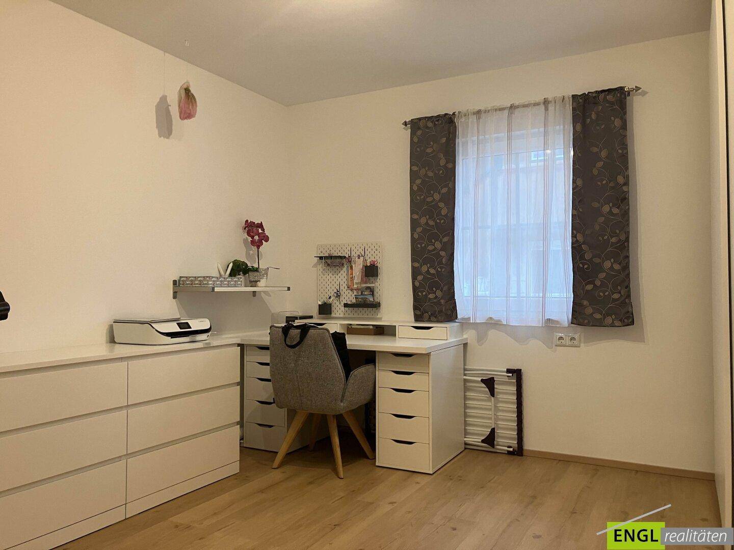 Funktional eingerichtetes Arbeitszimmer mit Schreibtisch, Kommode und Fenster für Tageslicht.
