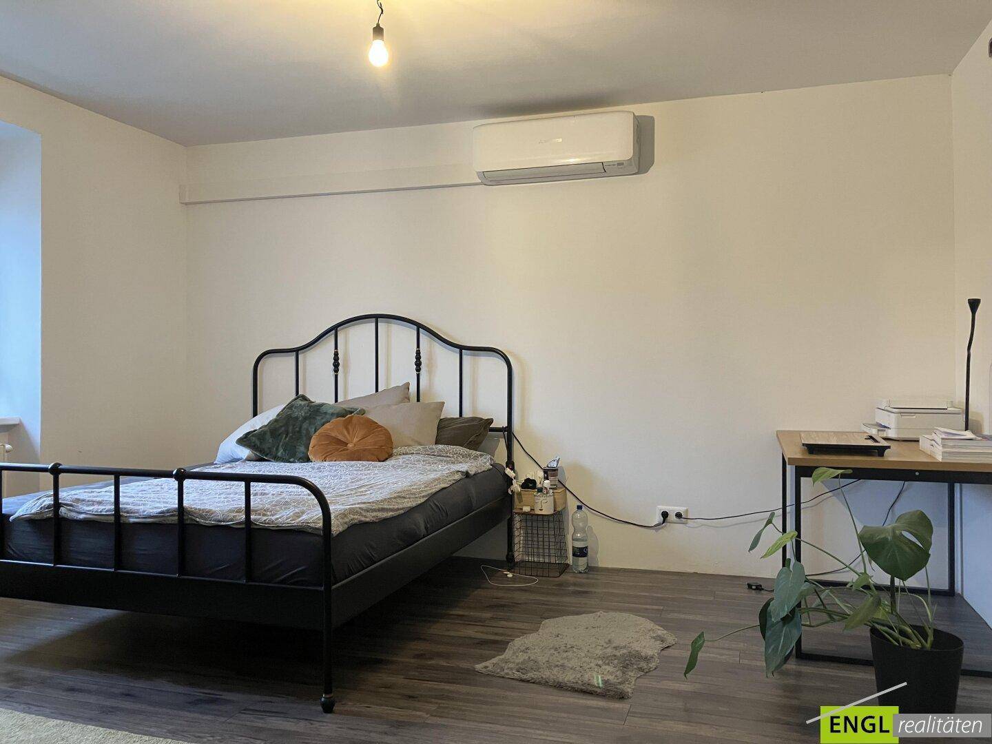 Schlafzimmer mit Doppelbett, Holzboden und Klimaanlage an der Wand.