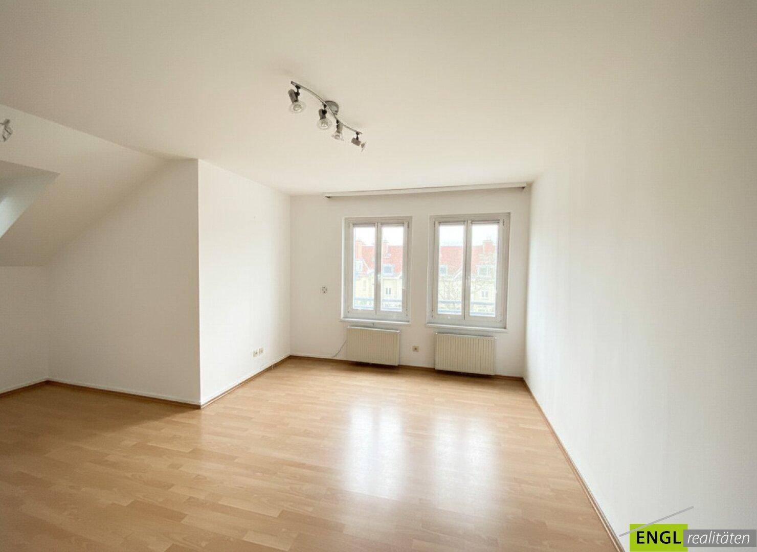 Heller Raum mit Parkettboden, zwei Fenstern und leichter Dachschräge, vielseitig nutzbar.