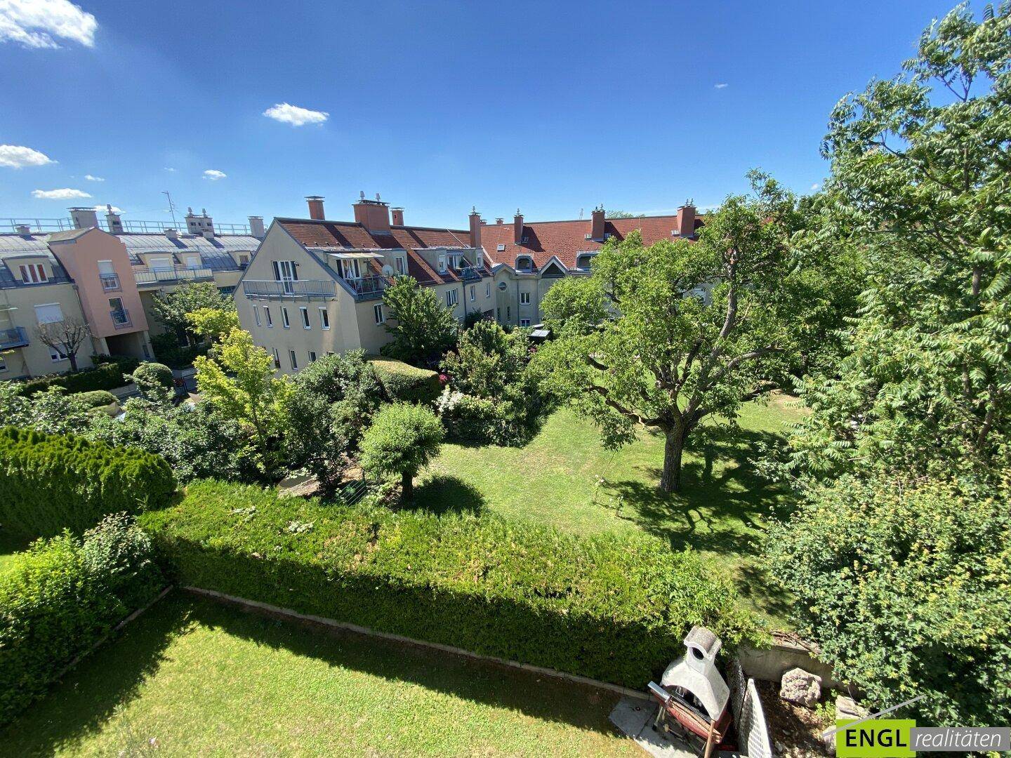 Weitläufiger Gartenbereich mit gepflegtem Rasen, altem Baumbestand und einem Grillplatz im Freien.