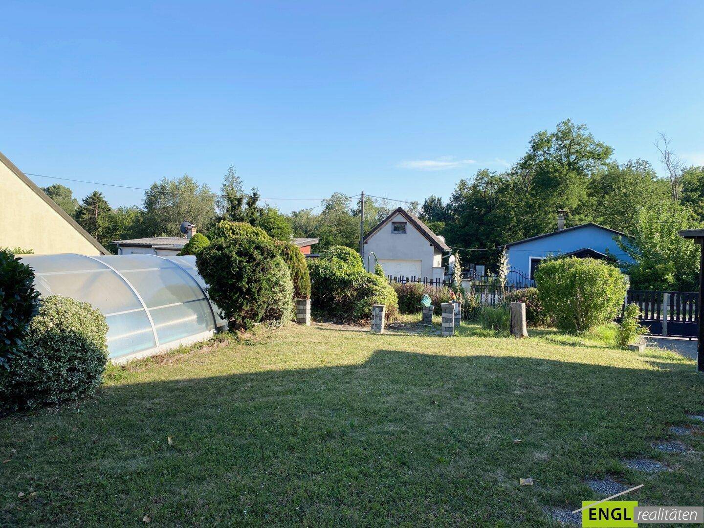 Großer Garten mit Rasenfläche und überdachtem Pool, umgeben von weiteren Wohnhäusern.