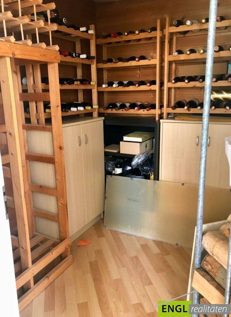 Geräumiger Weinkeller mit Holzregalen zur Lagerung zahlreicher Weinflaschen.