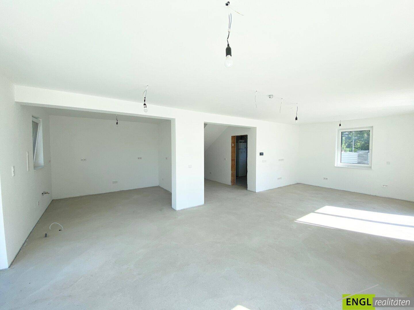 Weitläufiger Wohnbereich im Neubau mit hellen Wänden und vorbereiteten Anschlüssen für die Einrichtung.