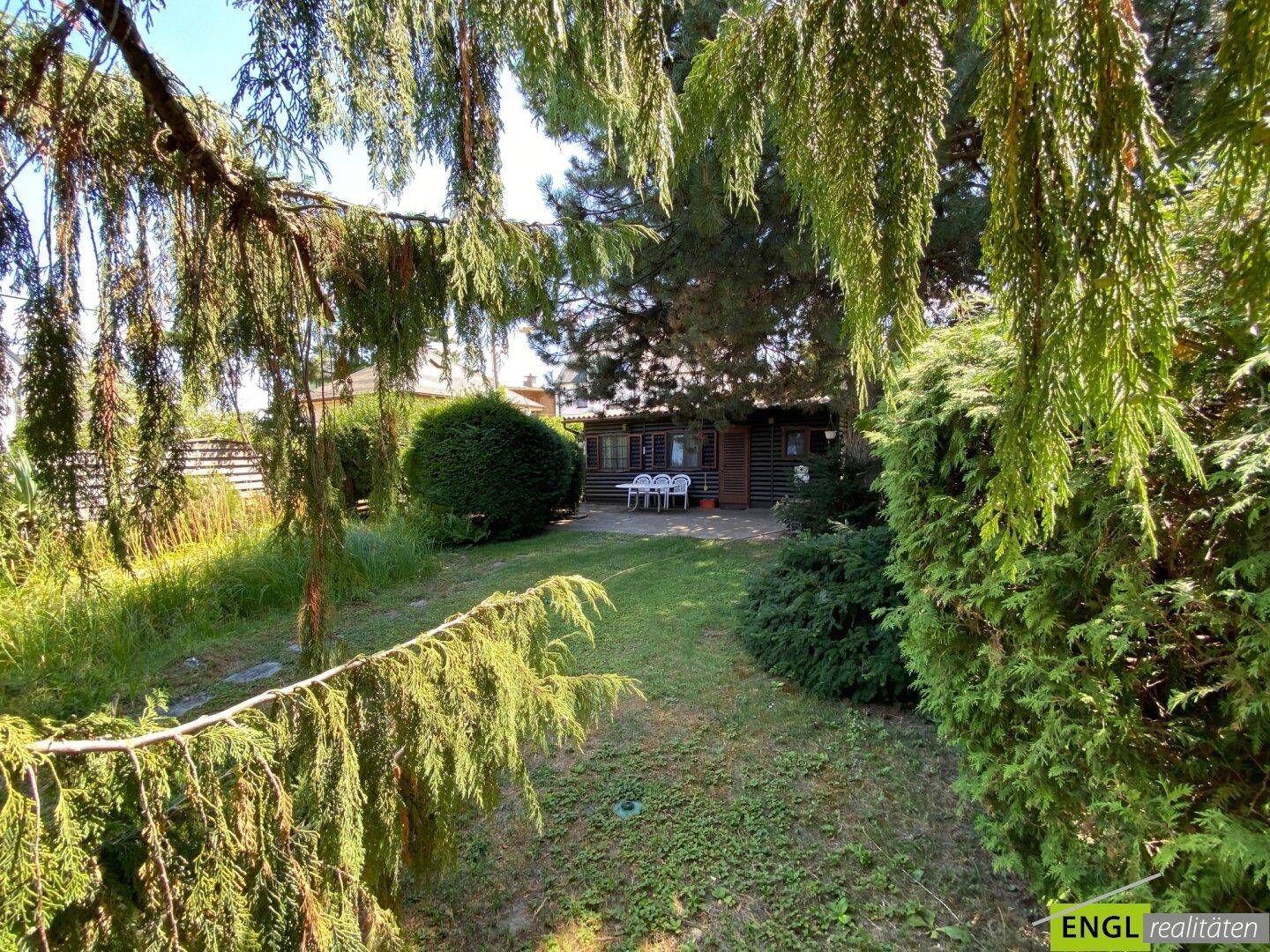 Idyllischer Gartenbereich mit üppiger Vegetation, Rasenfläche und einem charmanten Gartenhaus.
