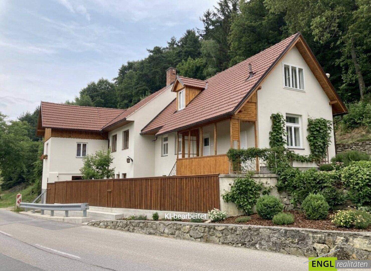 Renoviertes Haus mit neuem Dach und frischer Fassade, umgeben von gepflegter Landschaft und Bäumen.