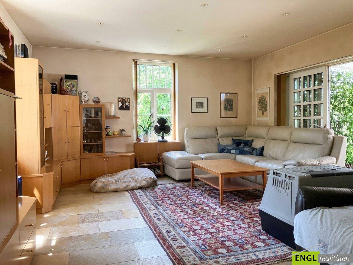 Geräumiges Wohnzimmer mit großem Ecksofa, Holzmöbeln und Fliesenboden, hell und einladend.