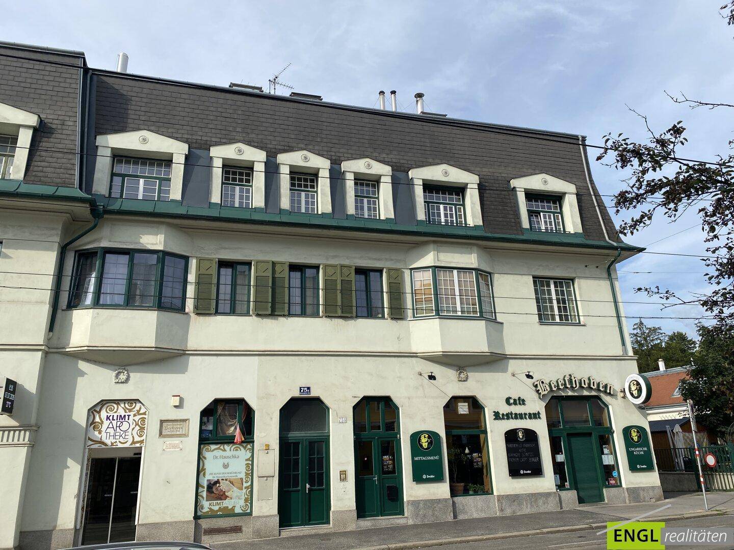 Historisches Gebäude mit Mansarddach, vielen Fenstern und einem Café im Erdgeschoss.