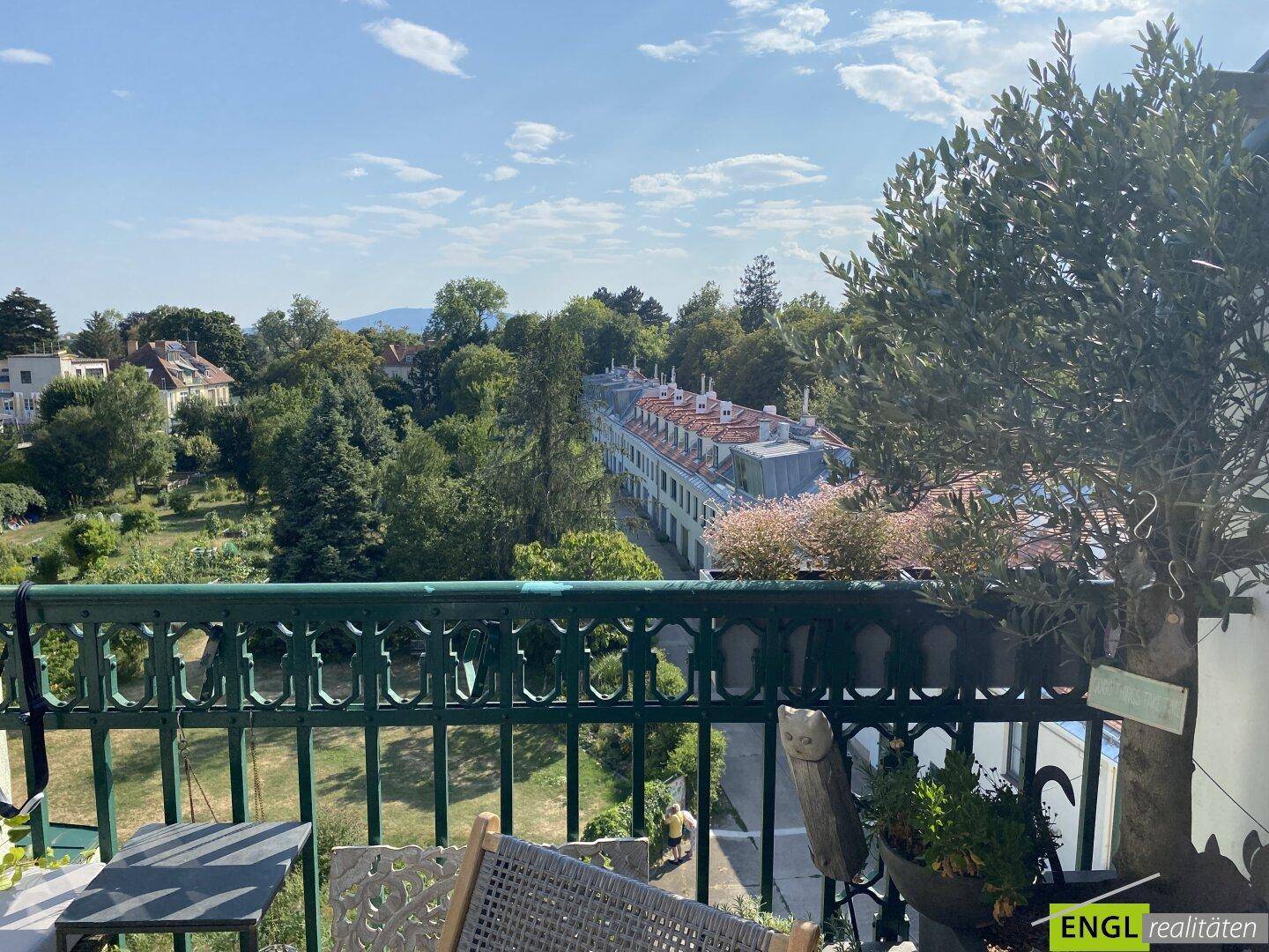 Weitläufiger Blick vom Balkon über grüne Baumwipfel und die umliegende Bebauung.