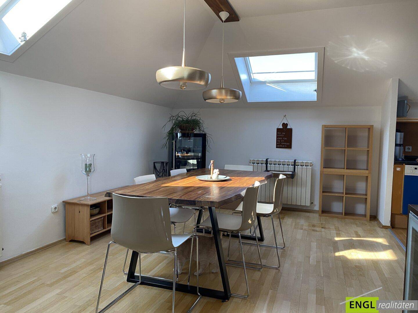 Heller Essbereich mit großem Holztisch, modernen Pendelleuchten und Dachfenstern.