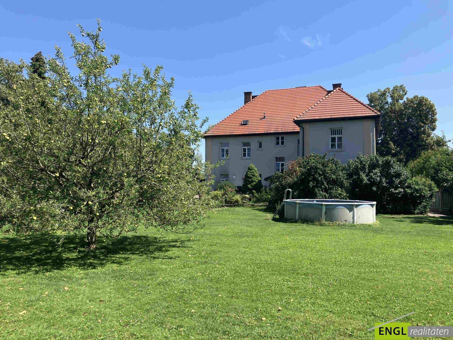 Großer Garten mit Rasenfläche, Obstbaum und einem Aufstellpool vor dem traditionellen Haus.