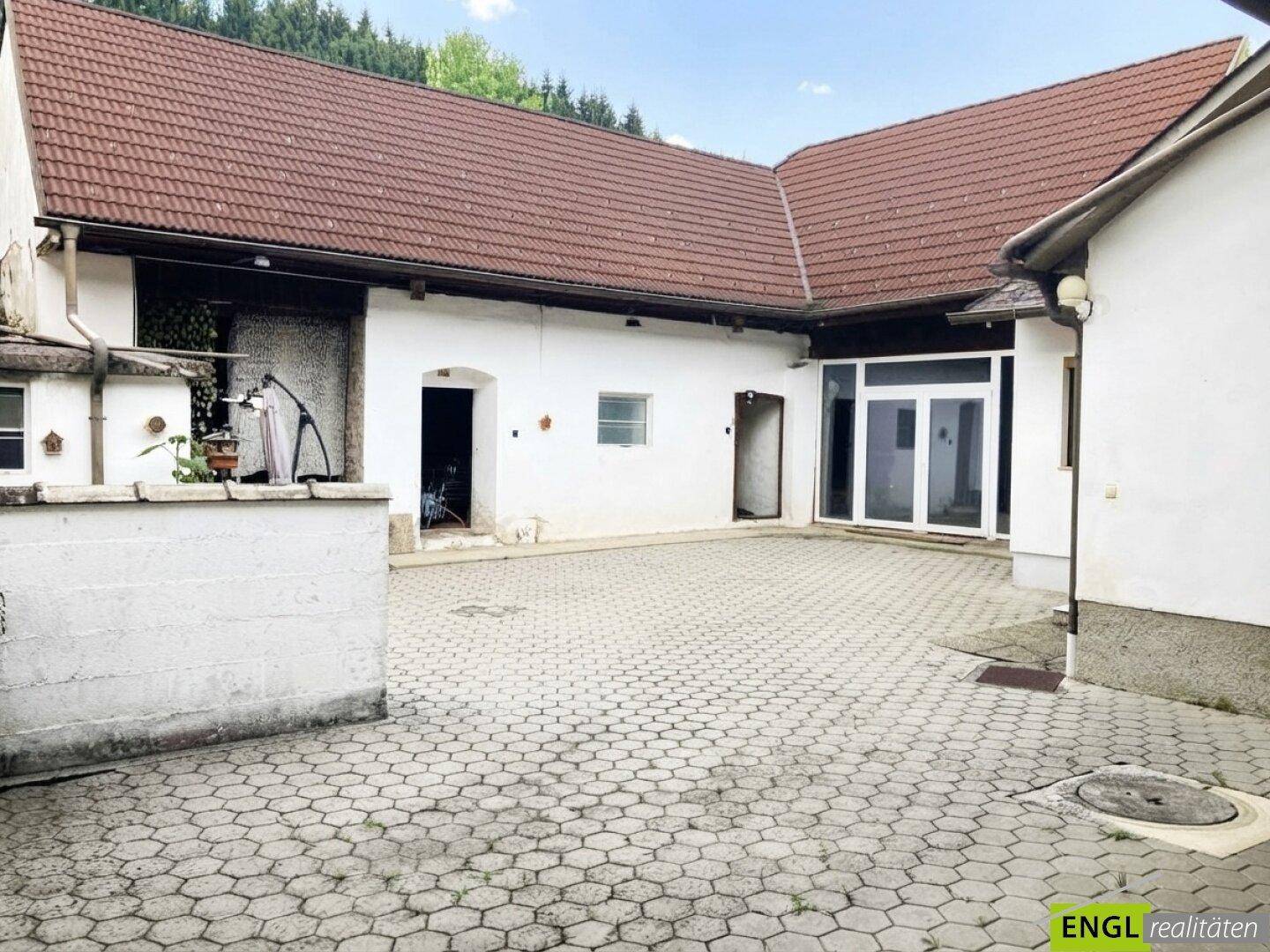 Gepflasterter Innenhof zwischen den Gebäudeteilen eines Anwesens mit traditioneller Architektur.