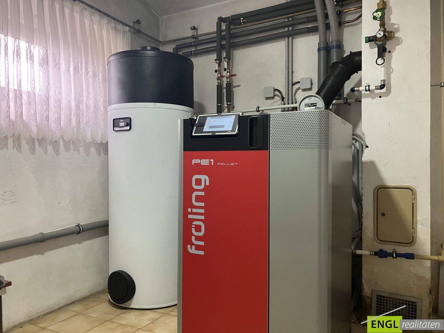 Heizraum mit einer modernen Froling Pelletheizung und einem großen Warmwasserspeicher.