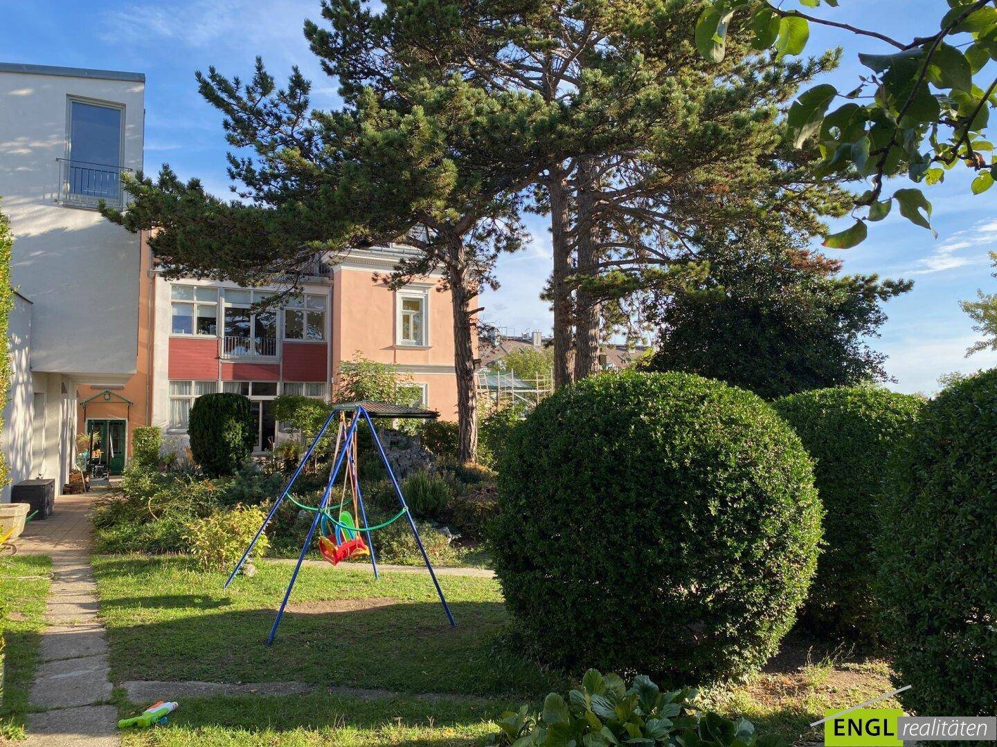 Großer Gartenbereich mit Schaukel, Rasenfläche und altem Baumbestand hinter dem Haus.