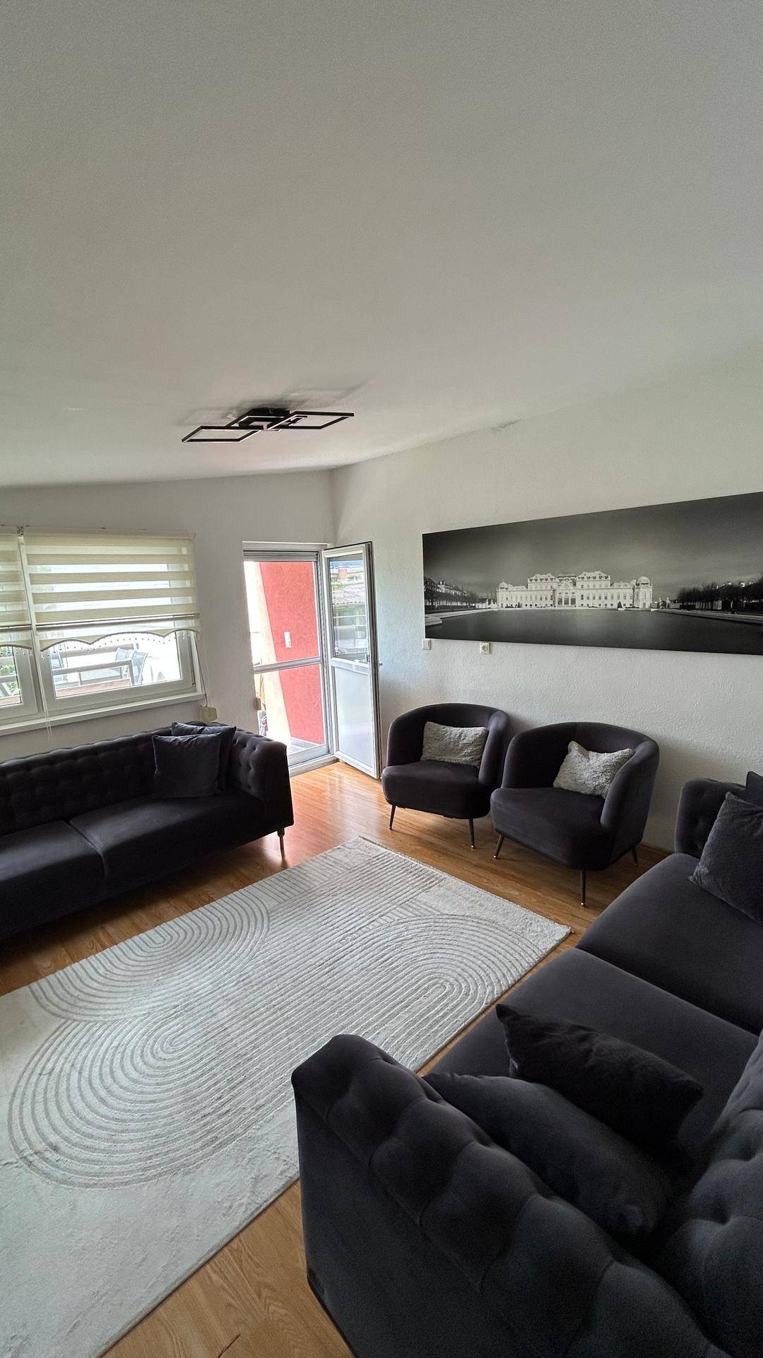 Geräumiges Wohnzimmer mit bequemen Sofas, Teppich und Zugang zu einem Außenbereich.