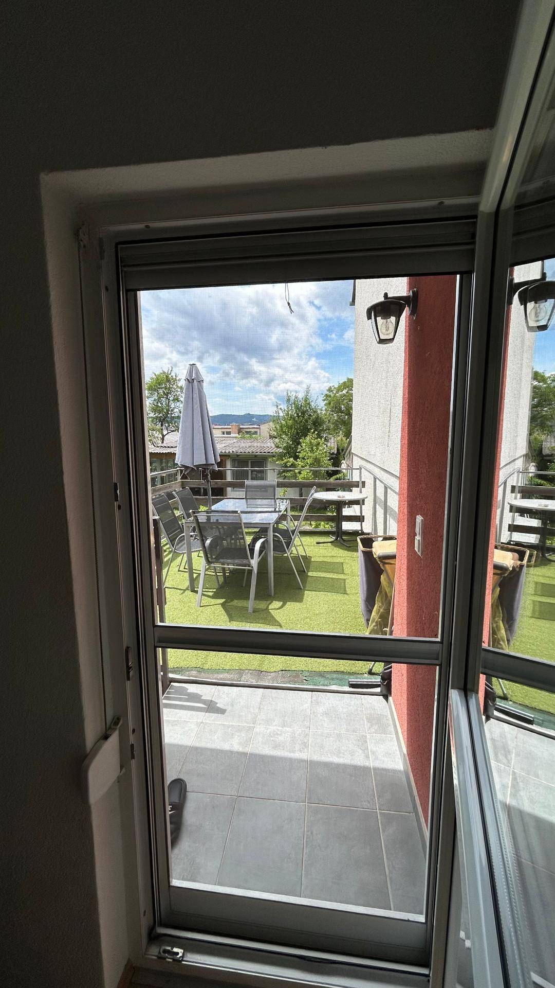 Blick auf die möblierte Terrasse mit Kunstrasen und Essbereich im Freien.