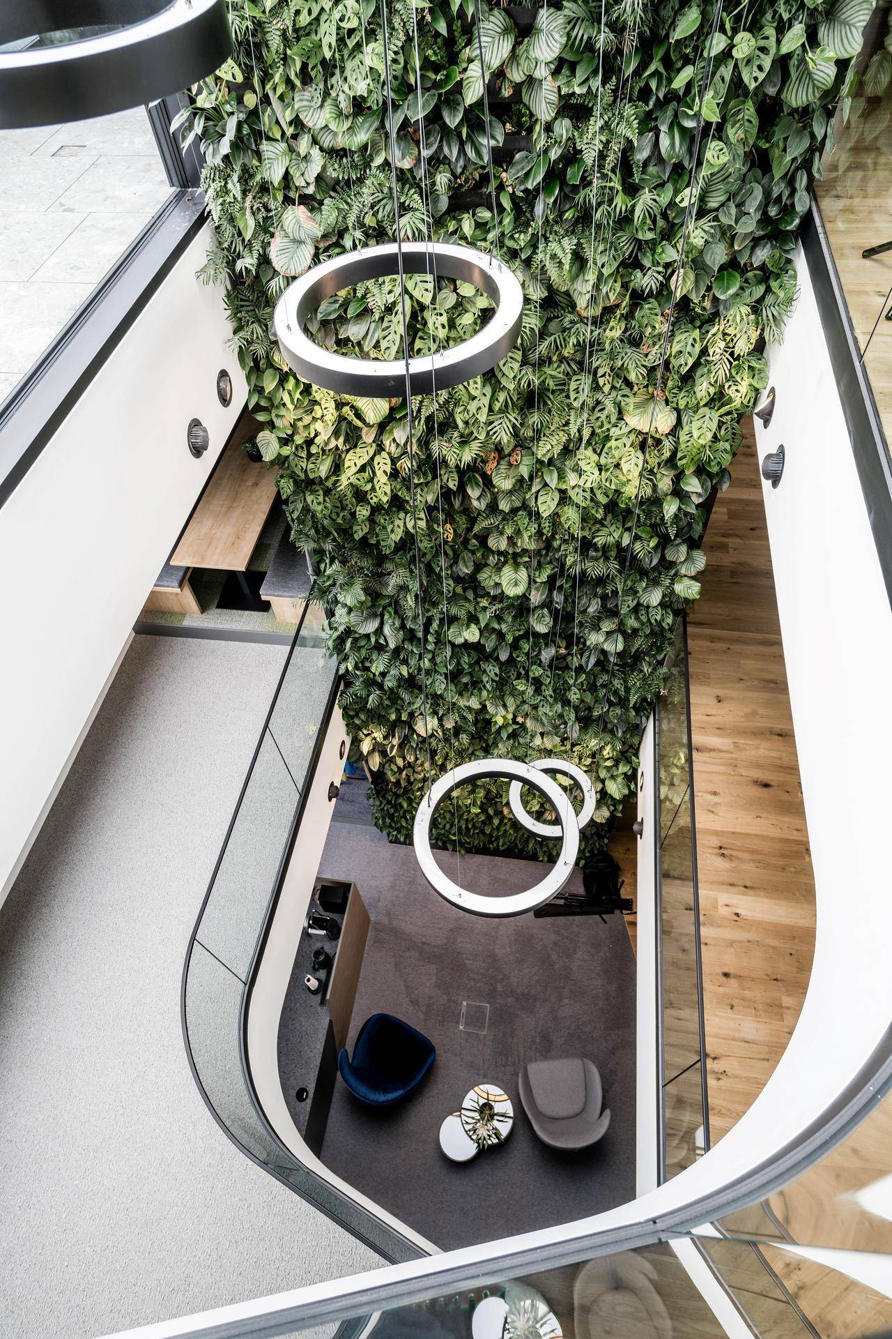 Beeindruckendes Atrium mit einer raumhohen grünen Wand, modernen runden Leuchten und einer gemütlichen Sitzecke.