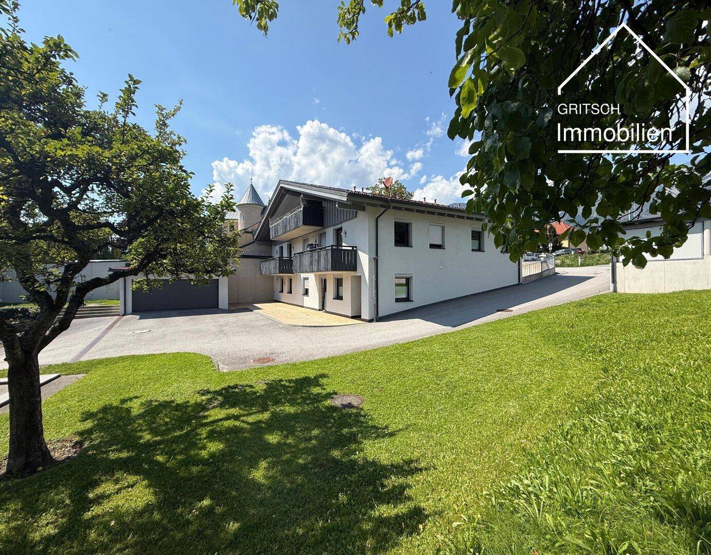 Gepflegter Gartenbereich vor einem modernen Haus mit Balkonen und viel Grünfläche.