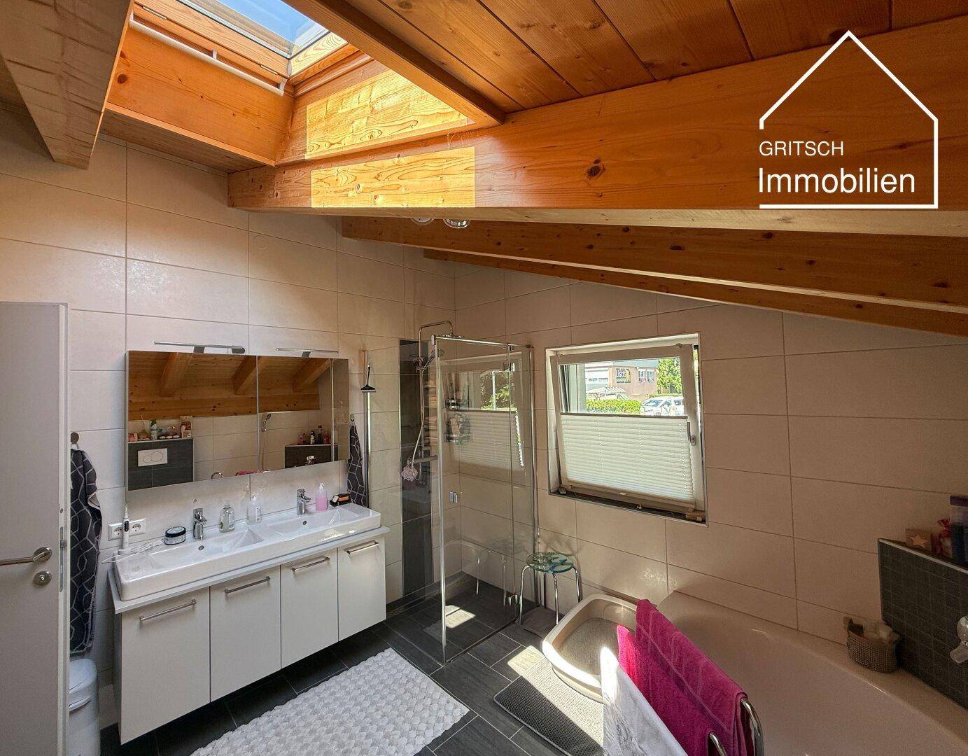 Modernes Badezimmer im Dachgeschoss mit Doppelwaschbecken, Dusche, Badewanne und Dachfenster.