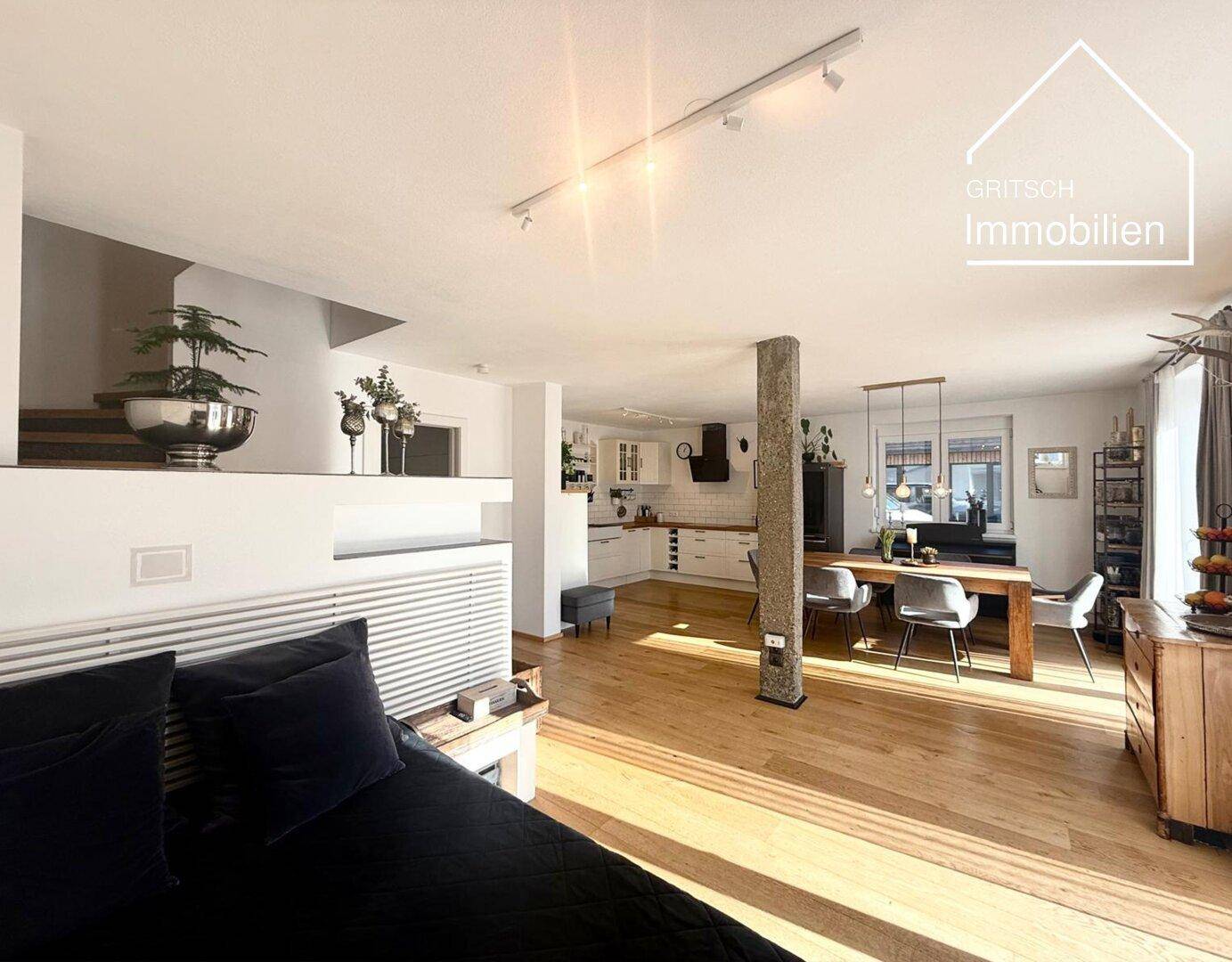 Geräumiger offener Wohnbereich mit Holzboden, Essbereich und moderner Küche, ideal für geselliges Beisammensein.