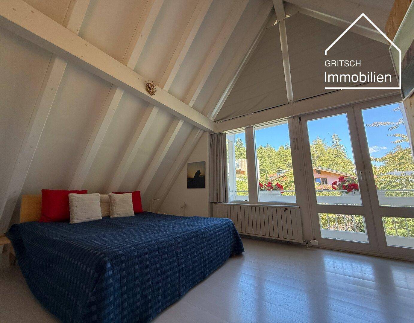 Helles Schlafzimmer mit großen Fenstern, Holzbalken und Blick ins Grüne, ideal zum Entspannen.