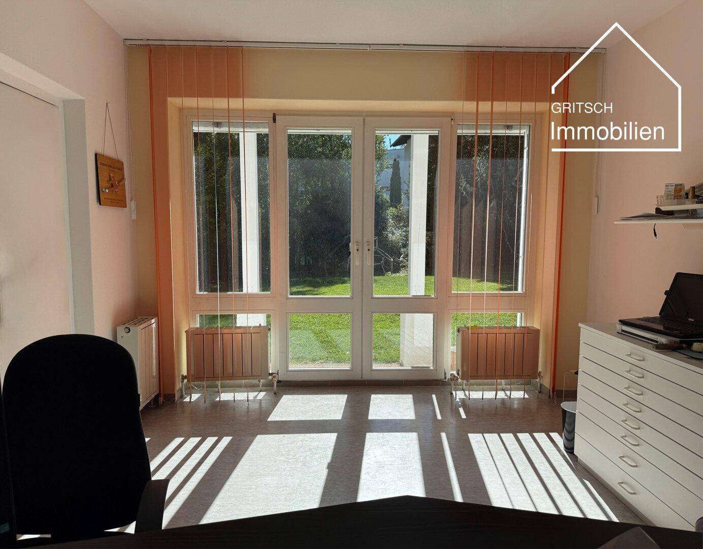 Funktionales Büro mit großen Fenstern und direktem Zugang zum Garten, bietet eine helle Arbeitsumgebung.