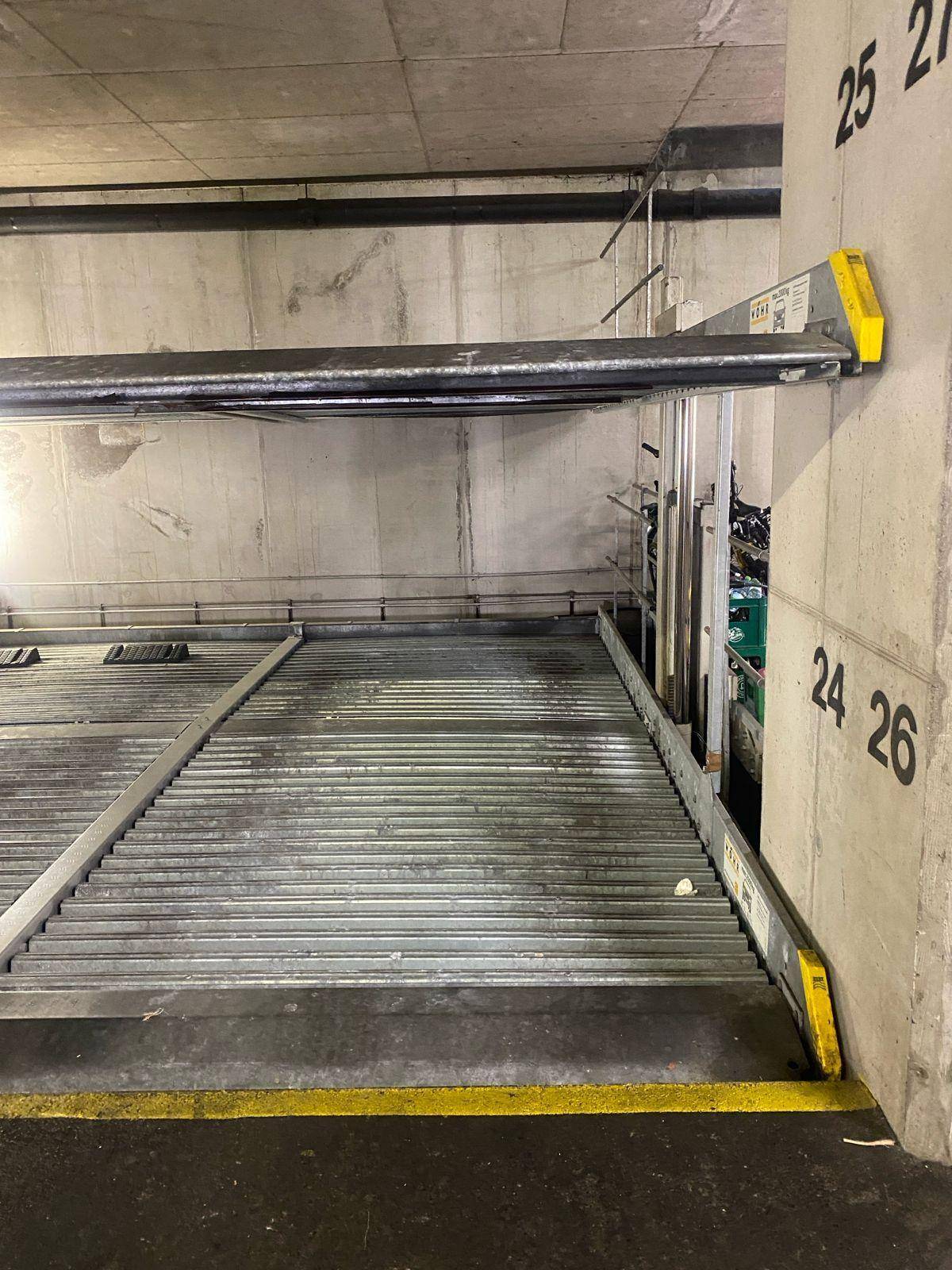 Leere untere Plattform eines mechanischen Doppelparkers in einer Tiefgarage, bereit zur Nutzung.