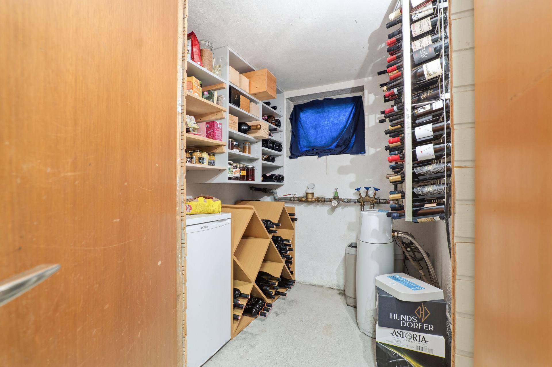 Gut ausgestatteter Weinkeller mit Regalen, Weinlagerung und kleinem Kühlschrank.