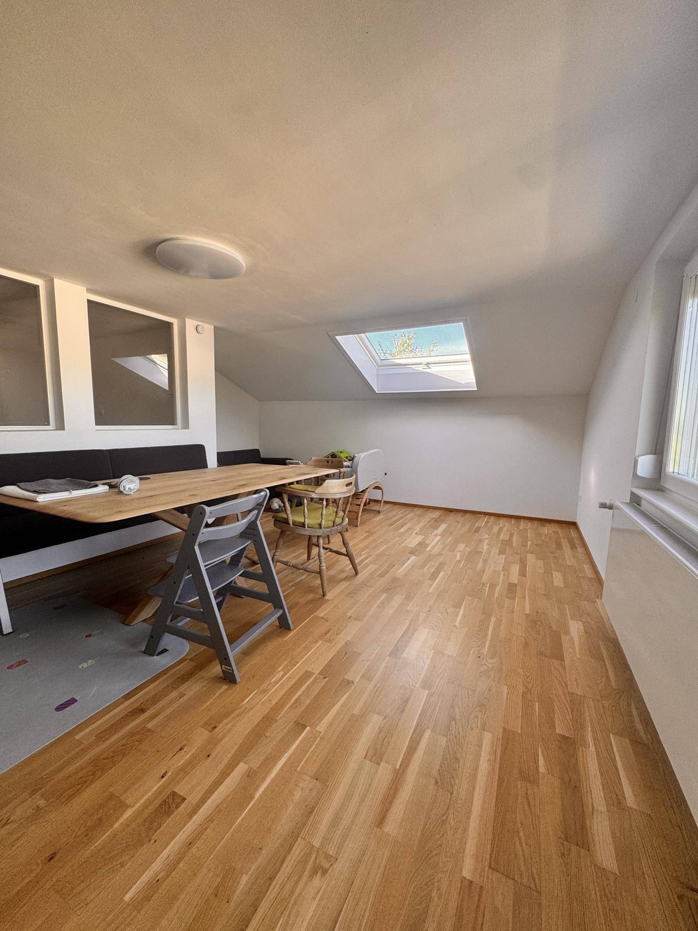 Geräumiger Essbereich mit Holztisch und Dachfenster, der viel Tageslicht hereinlässt.