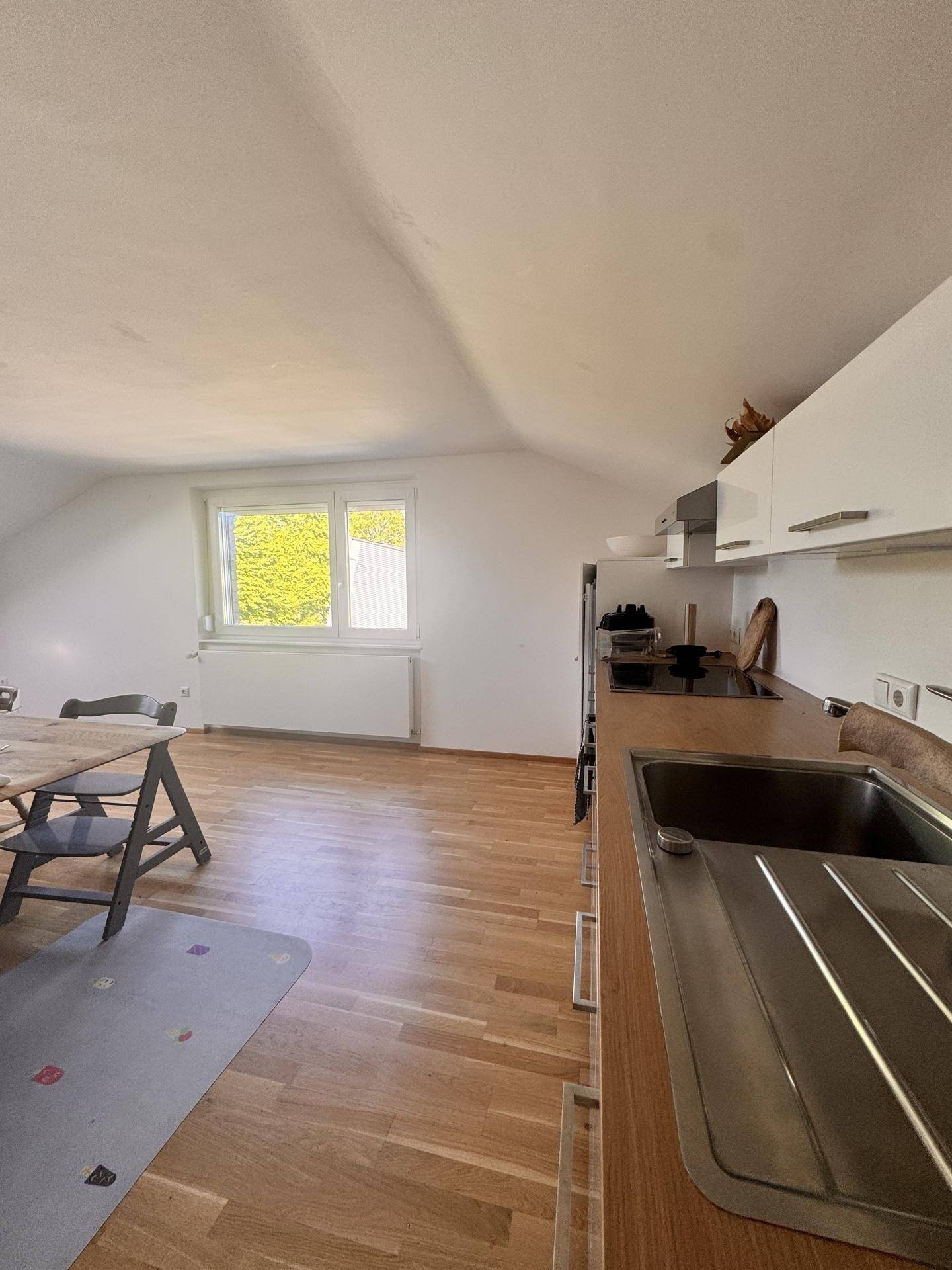 Funktionale Küche mit Holzarbeitsplatte, Spüle und einem Fenster mit Blick ins Grüne.
