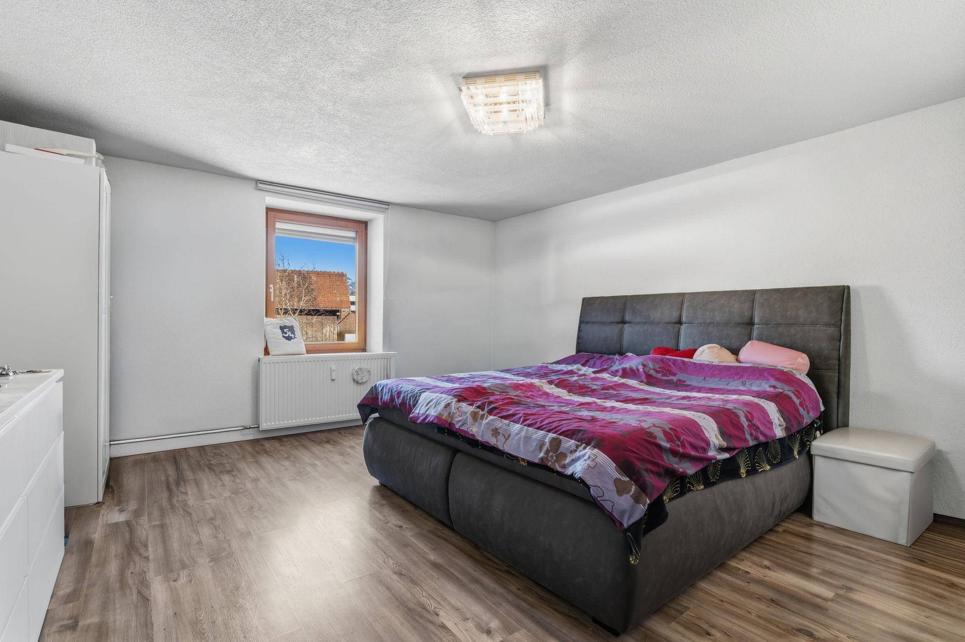 Helles Schlafzimmer mit großem Bett, Holzboden und Fenster mit Ausblick.