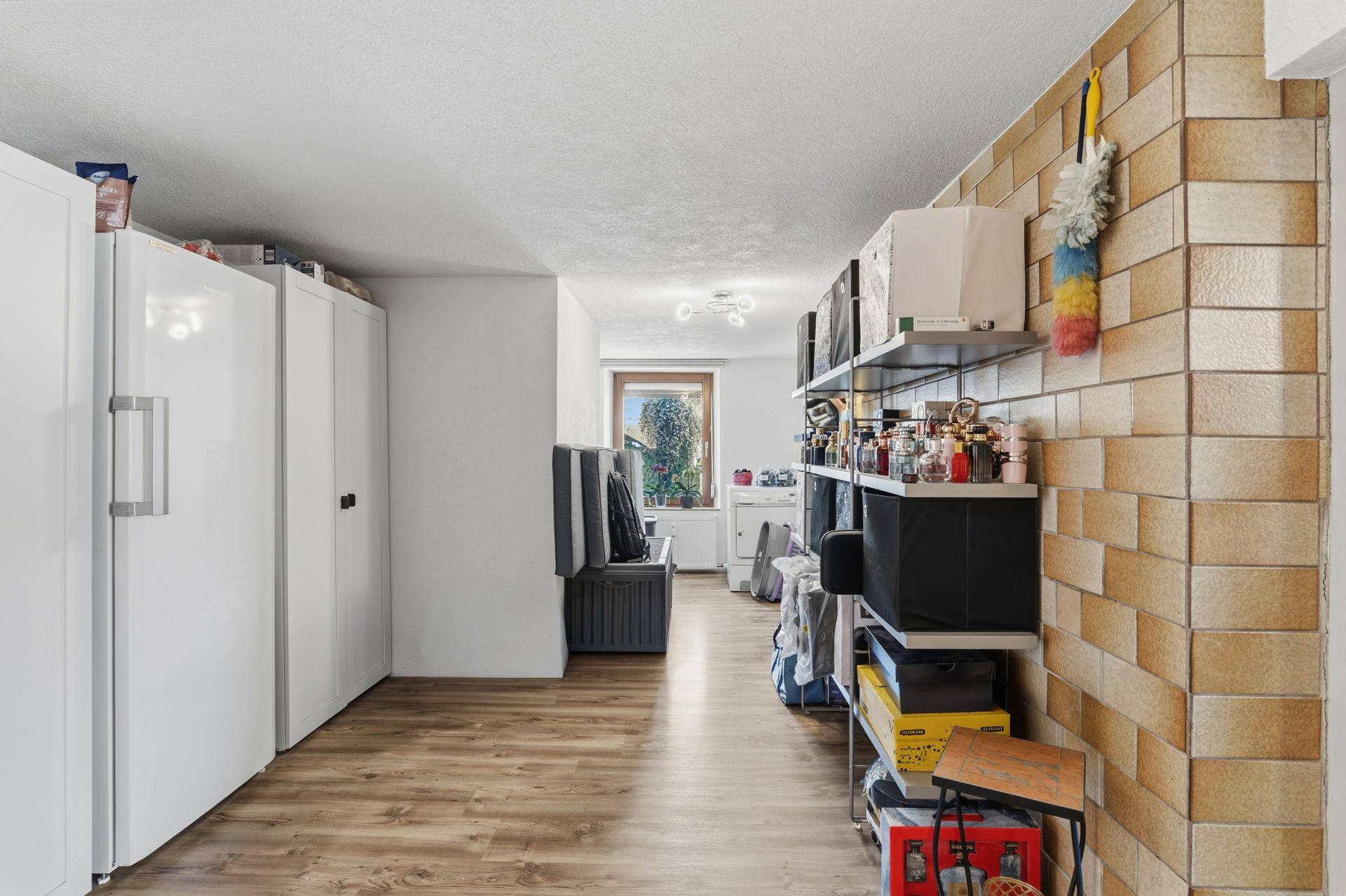 Praktischer Abstellraum mit Regalen, Kühlschränken und Fenster.