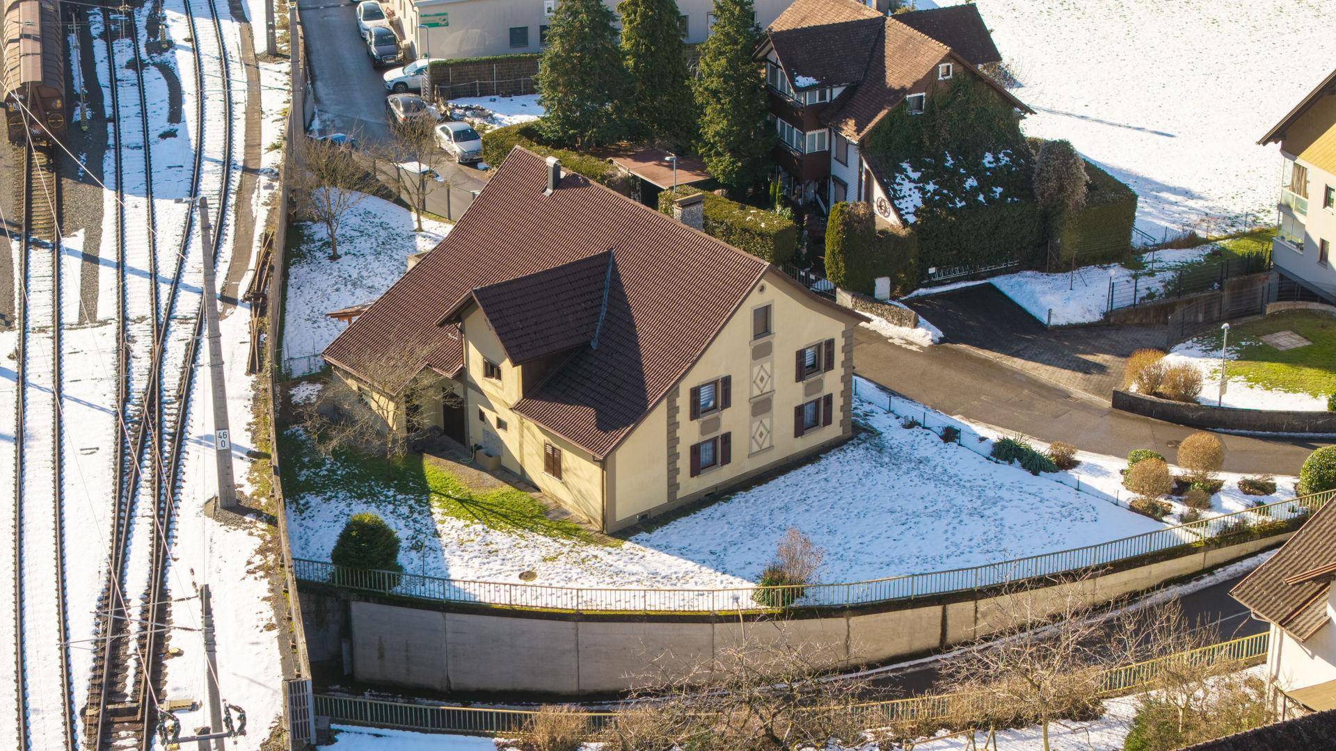 Vogelperspektive eines Einfamilienhauses mit Garten und angrenzenden Bahngleisen.
