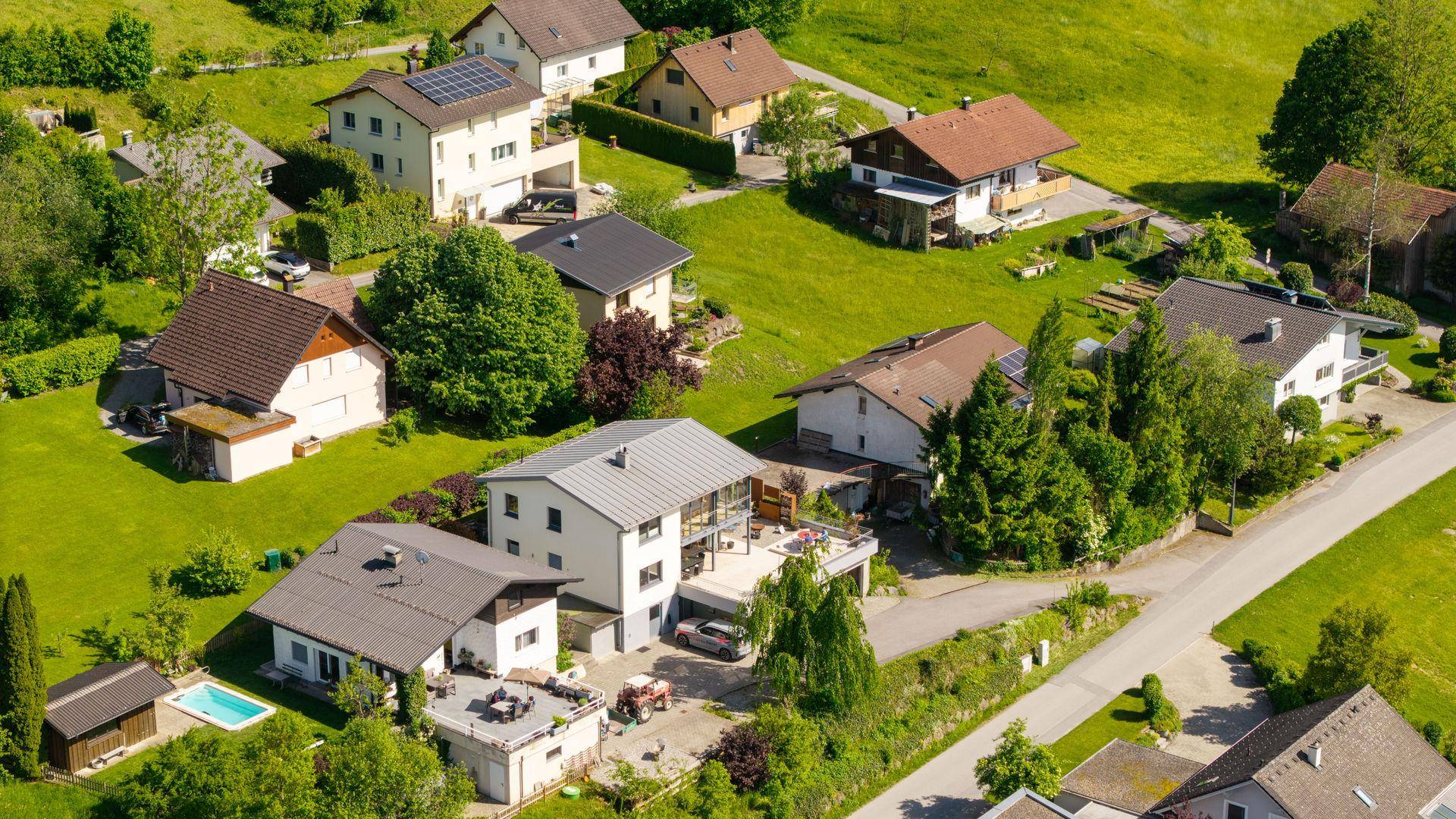Nahaufnahme aus der Luft einer Wohngegend mit Einfamilienhäusern und üppiger grüner Landschaft.